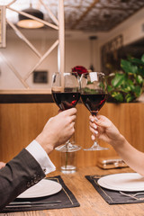cropped view of couple clinking with glasses of red wine during romantic date