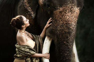 Asian traditional woman is taking care and hug her best friend elephant with love  at Kanchanaburi province in Thailand for the trips vacation .  Travel and Trips Concept