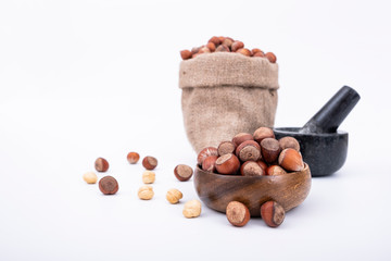 Hazelnuts with nutshell in bag and wooden bowl, hazelnuts on isolated white