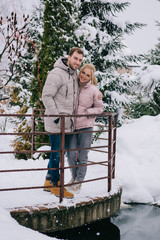 happy couple looking at camera and hugging in cold winter park