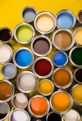 Tin cans with paint and brushes, yellow background