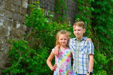 Fototapeta premium Brother and sister stand in an embrace in the park on the street and look at each other. The concept of happiness, family, love, unity and joy.