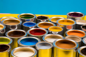 Full Buckets of rainbow colored oil paint on blue  background