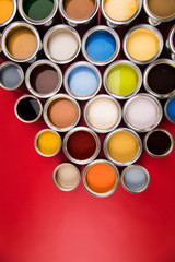 Collection of colored paints cans, red background