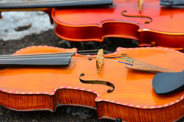 Two violins lie on the asphalt next to the snow
