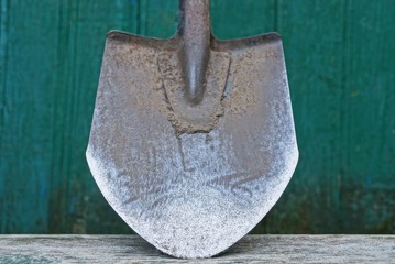 one old gray dirty iron shovel on a wooden board