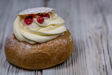 One Semla Cake with Cranberries on Old wooden Background .Close-Up