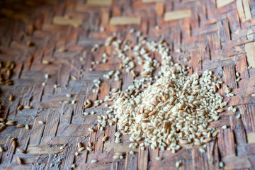 A pile of unpeeled and peeled rice in woven bowl