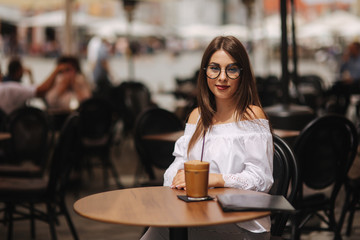 Stylish happy young woman wearing white shirt .She holds coffee. portrait of smiling girl in sunglasses