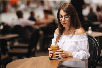 Stylish happy young woman wearing white shirt .She holds coffee. portrait of smiling girl in sunglasses