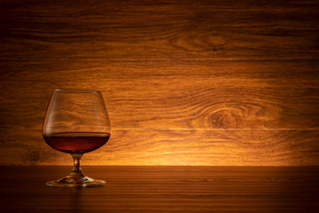 Brandy wine glass on wooden background. Cognac in a glass on a wooden table