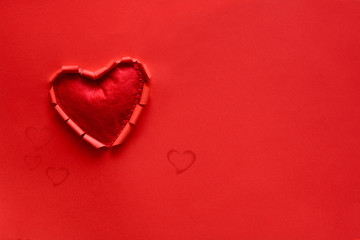 Ripped paper hole heart shaped with felt heart on red paper background. Valentine's day celebration concept