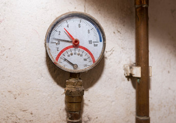 Pressure gauge, manometer on copper pipe close up shot, part of the wooden central heating system.