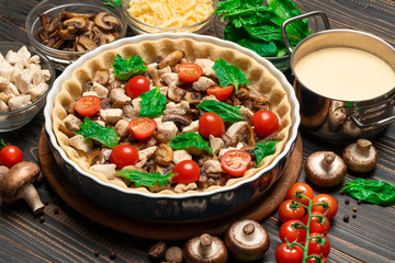 Traditional quiche tart in baking form with filling and ingredients