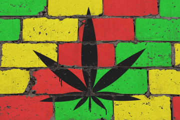 Cannabis leaf depicted on brick colored wall in style of rasta. Graffiti street art spray drawing...
