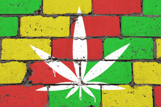 Cannabis leaf depicted on brick colored wall in style of rasta. Graffiti street art spray drawing on stencil.