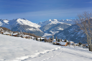 Fototapeta na wymiar track in the snow going to an alpine french village in snowy mountain