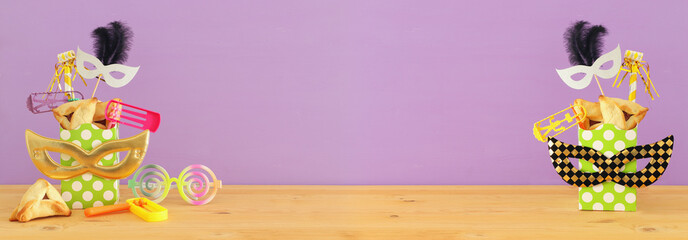 Purim celebration concept (jewish carnival holiday) over wooden table and pink background.