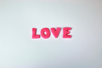 Pink plasticine and clay letters spelling the word Love isolated on white background