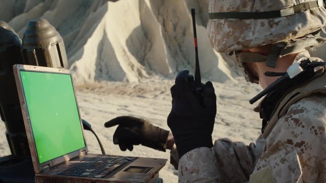 Military Operation in the Desert: Soldier Works on Green Choma Key Screen Laptop, Uses Radio Communication.