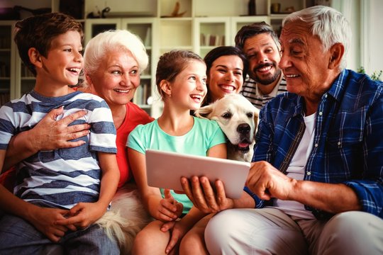 Happy multi-generation family using digital tablet in living