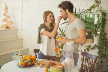 happy pretty girl giving a grape for her boyfriend while preparing drink. happy mood in the kitchen.care