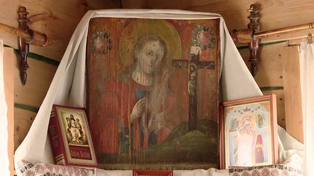 An icon depicting the Virgin Mary of Our Lady, decorated with a towel with a bedspread in a wooden house in the red corner. Rushnik. Russian tradition.