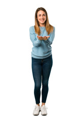 Full body of Blonde woman with blue shirt holding copyspace imaginary on the palm to insert an ad on white background