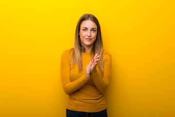 Obraz premium Young woman on yellow background applauding after presentation in a conference