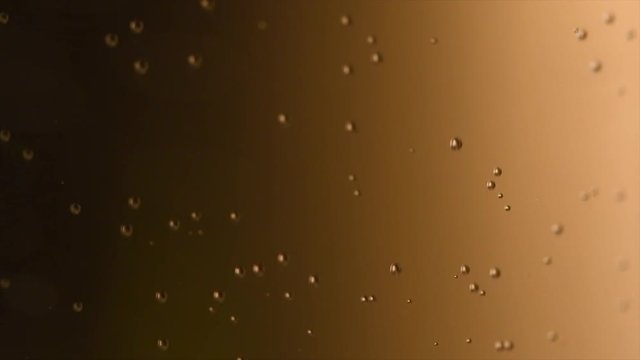Champagne bubbles background closeup. Sparkling wine gold backdrop. Bubbly fizzing champagne closeup. Slow motion 4K UHD video footage. 3840X2160