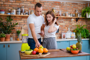Young couple making smoothie in kitchen