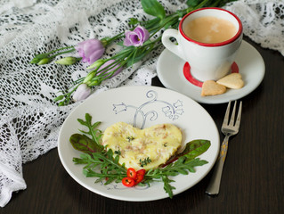 Omelet with tuna and green salad, cup of coffee with cookies in the shape of a heart against the background of delicate flowers. Valentine's day or Mother's Day breakfast concept. Selective focus