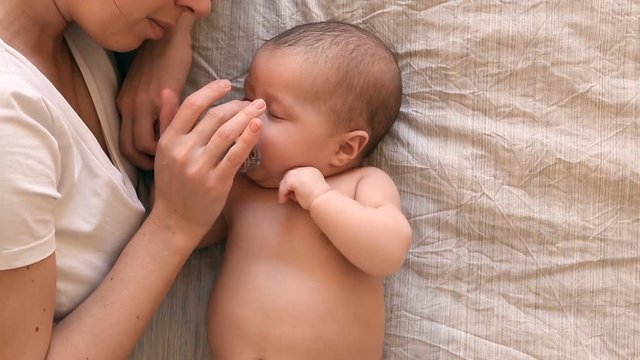 Young mother holding her newborn sleeping baby, puts the baby to sleep