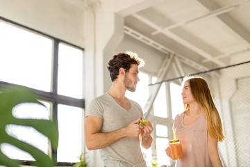 young attractive man with an apple looking at the pleasant grl with a glass of juice. close up photo. copy space