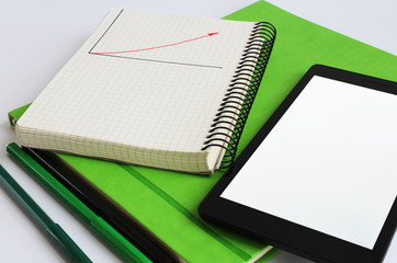  A laptop and notebook are on a green weekly.  Nearby are markers of green and black colors