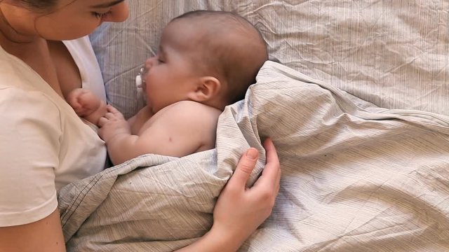 Young mother holding her newborn sleeping baby, puts the baby to sleep