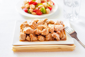 Turkey stew in tomato mustard sauce with onion on square plate