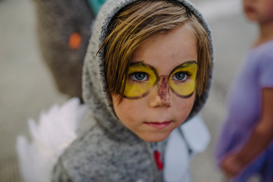 Cute boy with face paint wearing costume looking away during Halloween party