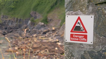 A 'Danger Loose Cliffs' warning sign in Cadgwith, Cornwall, England.