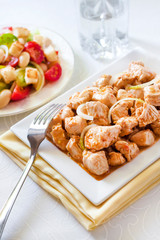 Turkey stew in tomato mustard sauce with onion on square plate