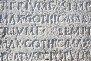 Latin inscriptions background wallpaper on an ancient cracked marble slab in Rome.