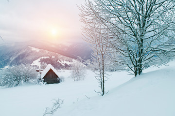 Carpathian mountain village in light of rising moon with wooden houses on a hill covered with fresh snow. Fantastic milky way in a starry sky. Christmas winter night.