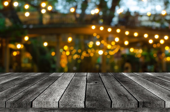 empty wooden board, table or modern wooden terrace with abstract night light bokeh of restaurant at night festival in garden, copy space for display product or object presentation, vintage color tone