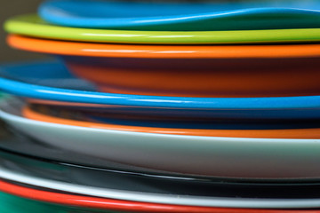 A stack of colored plates close-up on a wooden background.