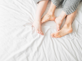 Feet of two couple sleeping on bed under blanket. Love and relationship concept