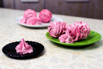 Homemade marshmallow with currant juice lies on the colored plates on the kitchen table.