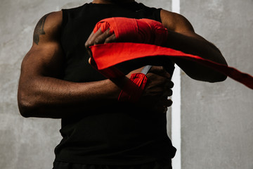 Midsection of man wrapping hands with boxing tape