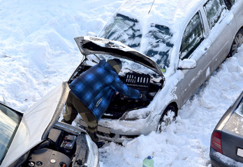мужчина ремонтирует легковой автомобиль в зимний...