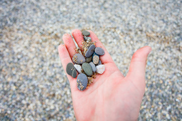 Pebbles lying in man hand close up. Travelling to sea