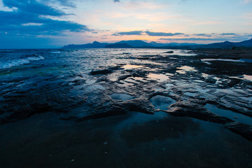 Fototapeta premium Rocky shore washed by sea waves in evening. Marine landscape
